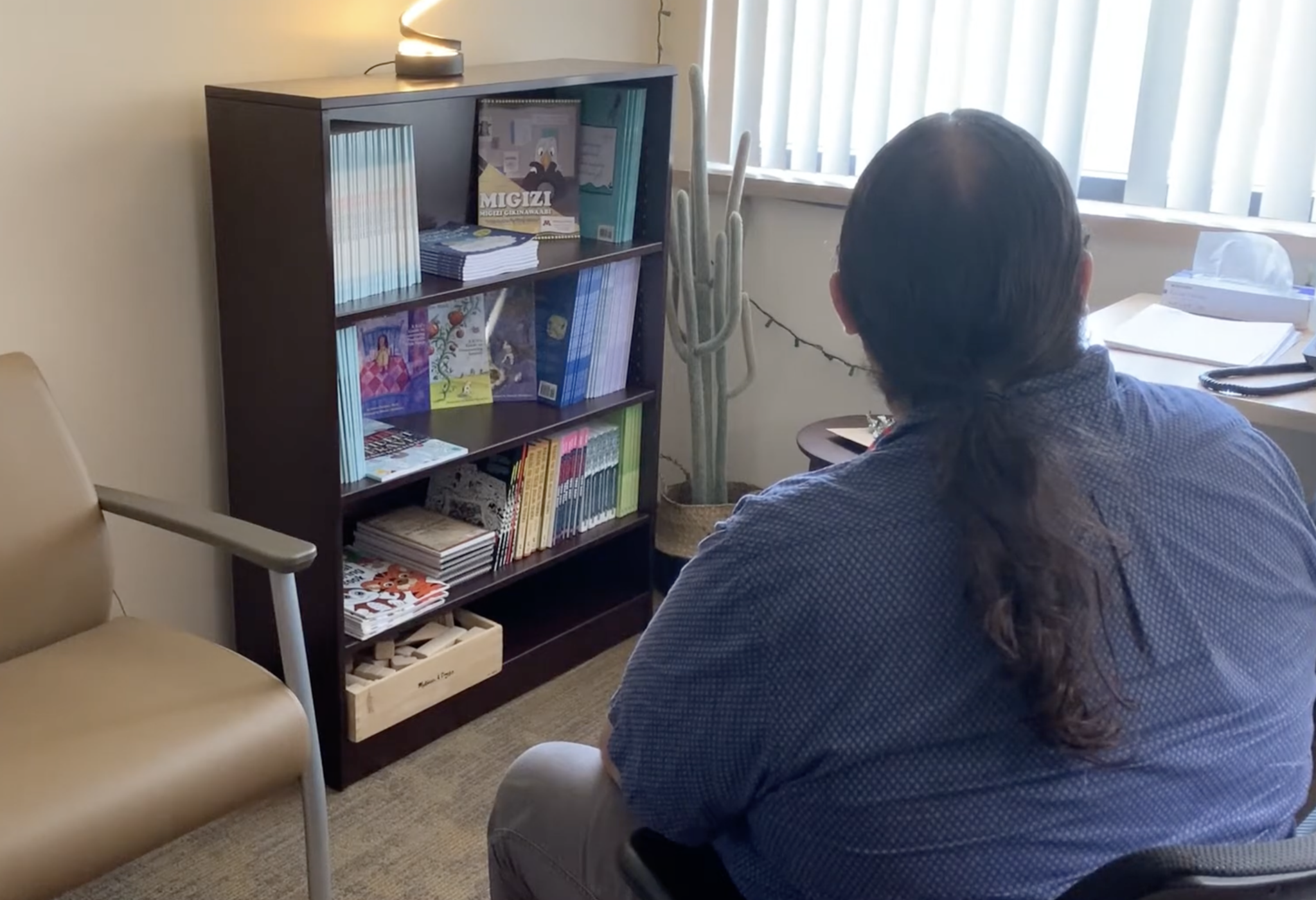 a person sitting in a chair looking at a book shelf
