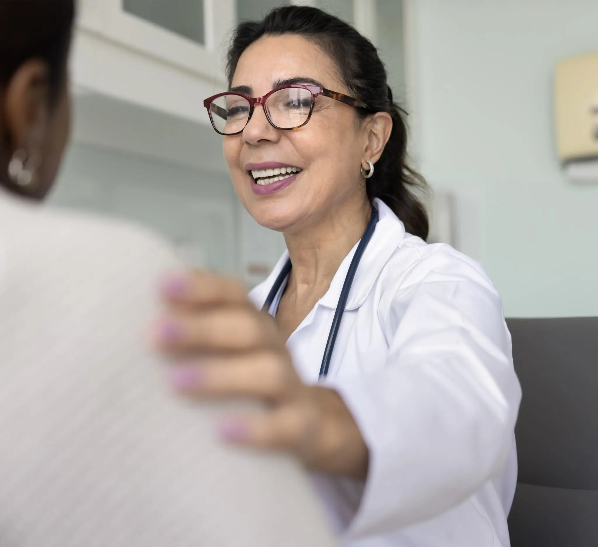 a person in a white coat and glasses talking to a patient